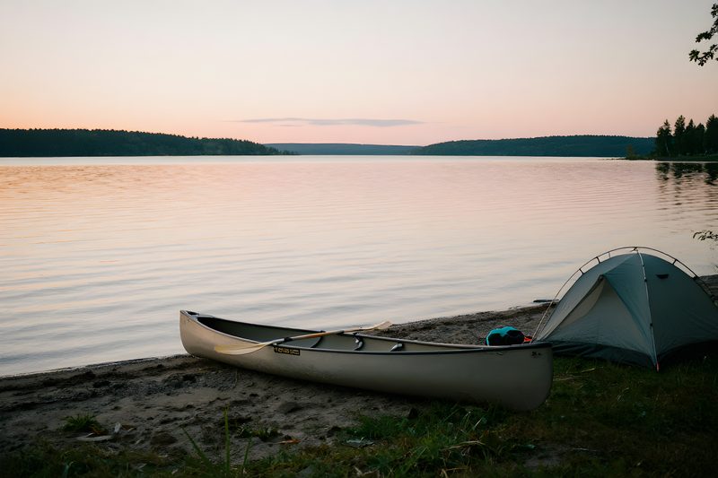 Kanot uppdragen vid ett strandläger i skymning under en paddlingstur